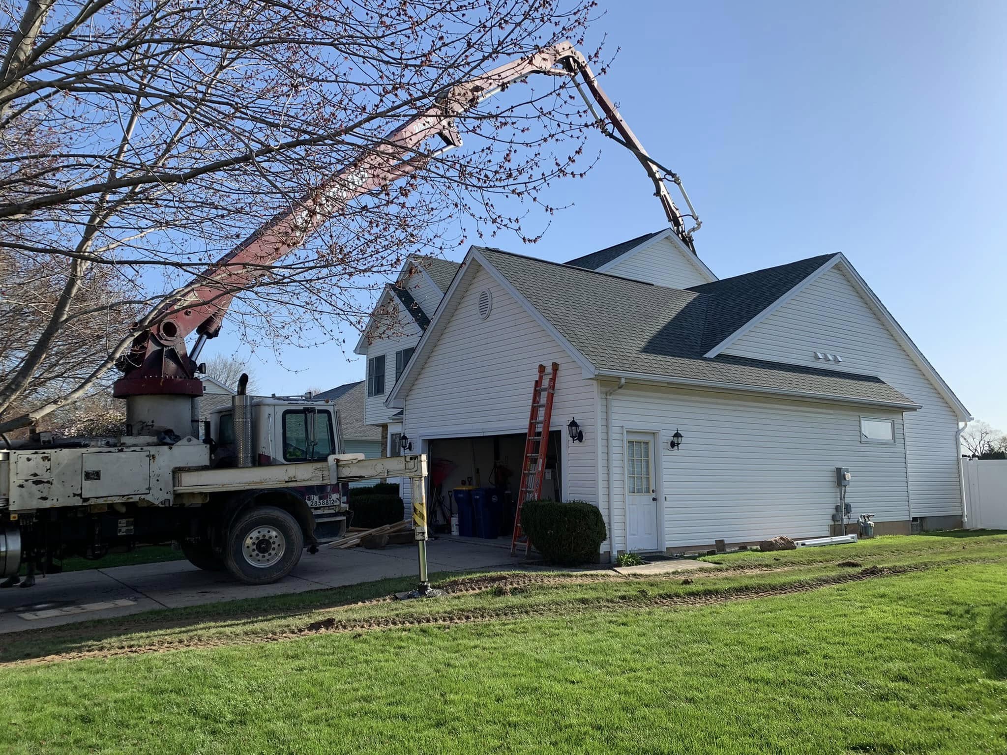 Construction truck with extended boom arm positioned at a residential home during addition and renovation work.