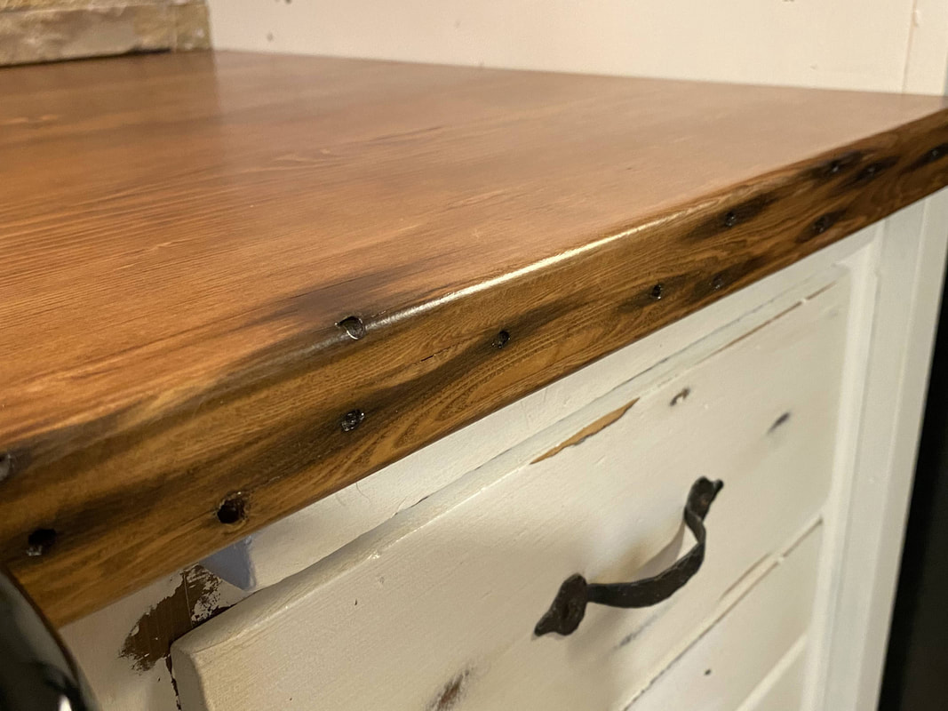 Close‑up of reclaimed barn‑wood edge with natural texture and stone backsplash in a rustic kitchen remodel.