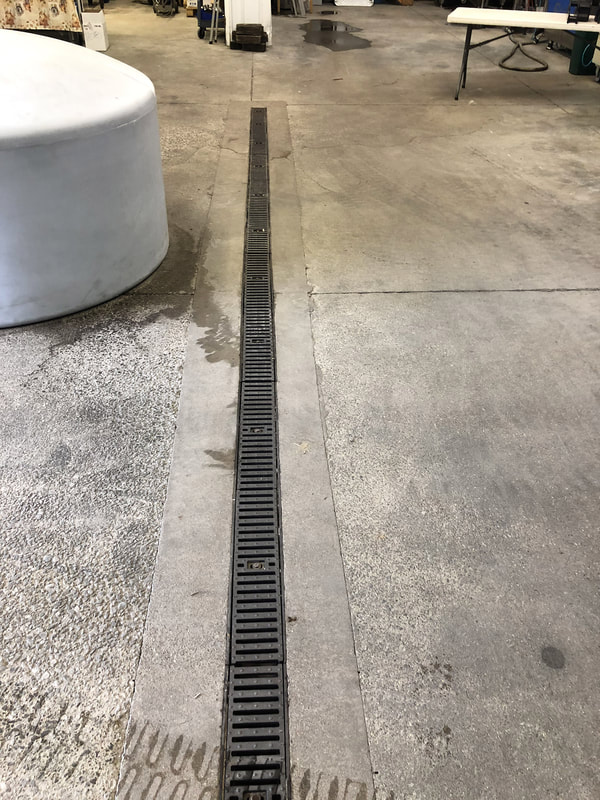Floor with trench drain and metal grate designed for water runoff and cleaning.