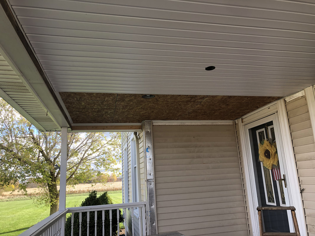 Front porch ceiling partially finished with vinyl panels and OSB section awaiting completion.