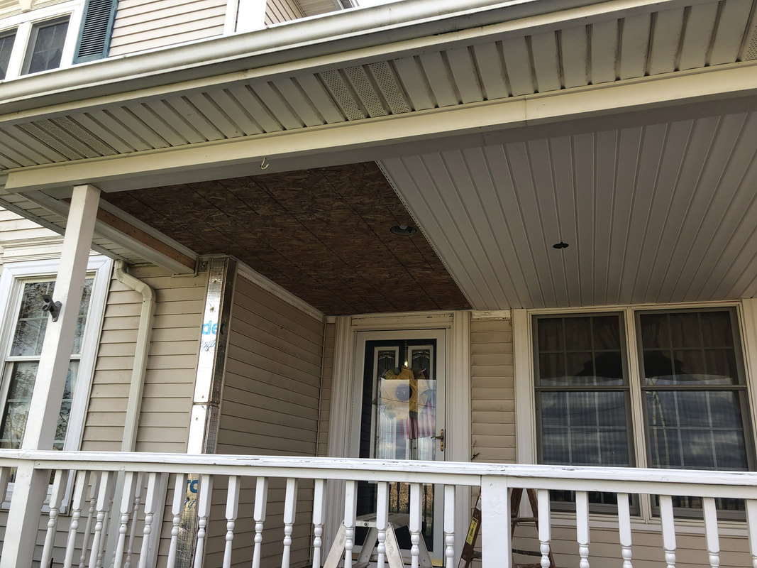 Front porch ceiling partially finished with vinyl panels and OSB section awaiting completion.