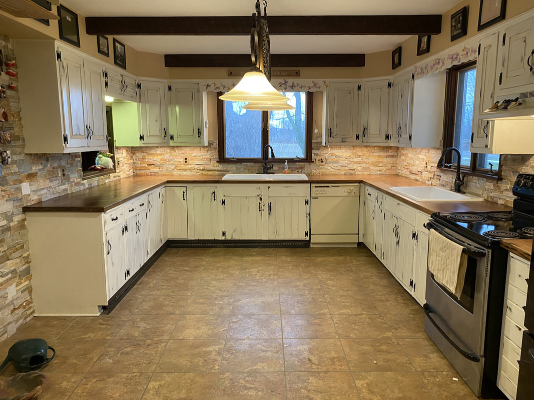 Completed kitchen remodel with reclaimed barn‑wood countertops, white cabinets, stacked‑stone backsplash, and farmhouse‑style sink.